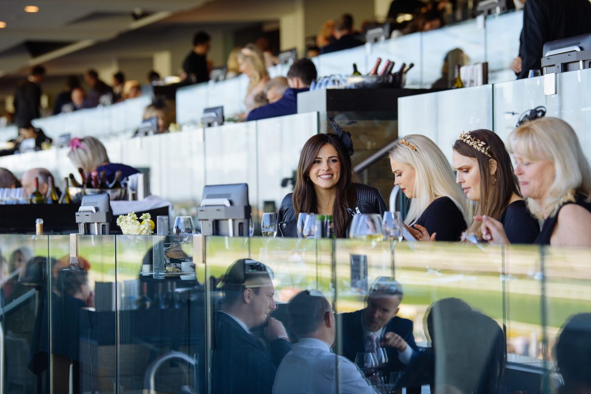 A group of women at a restaurant in a grandstand at a racecourse